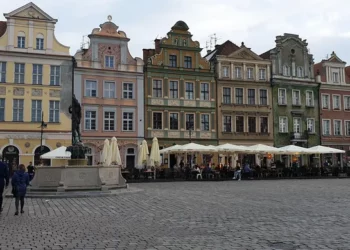 Stary Rynek w Poznaniu jesienią – ludzie spacerują w chłodny, pochmurny dzień.