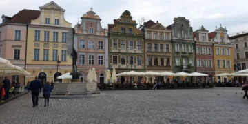 Stary Rynek w Poznaniu jesienią – ludzie spacerują w chłodny, pochmurny dzień.