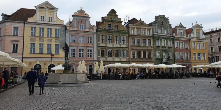 Stary Rynek w Poznaniu jesienią – ludzie spacerują w chłodny, pochmurny dzień.